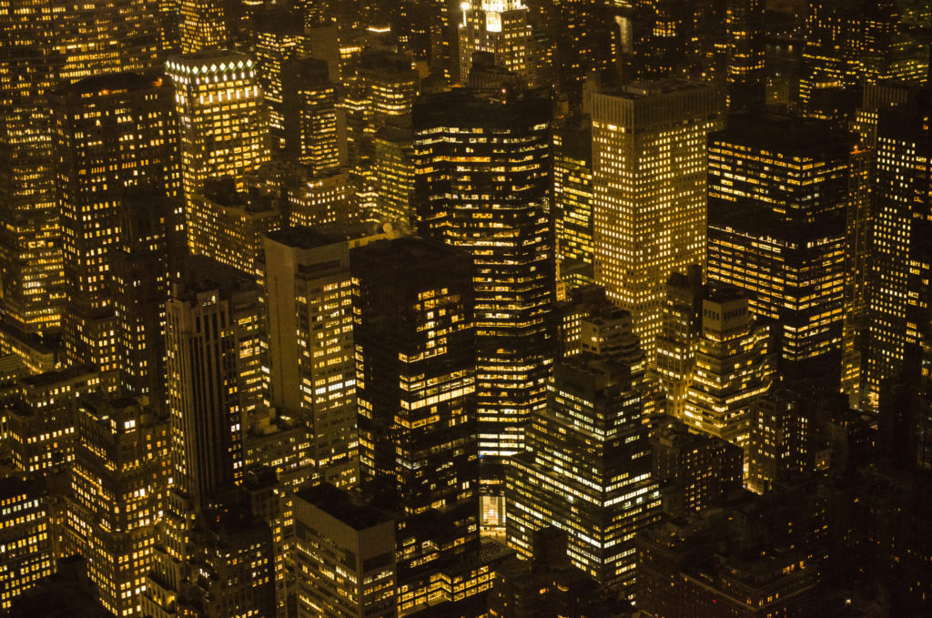View of skyscrapers in Midtown Manhattan, New York with lights on at night