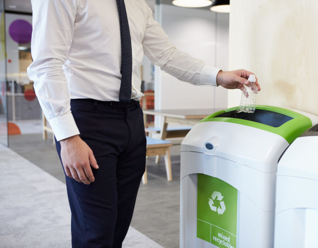Man places waste in a recycle bin at work